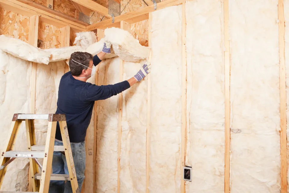 Installer fitting batt insulation between wall studs