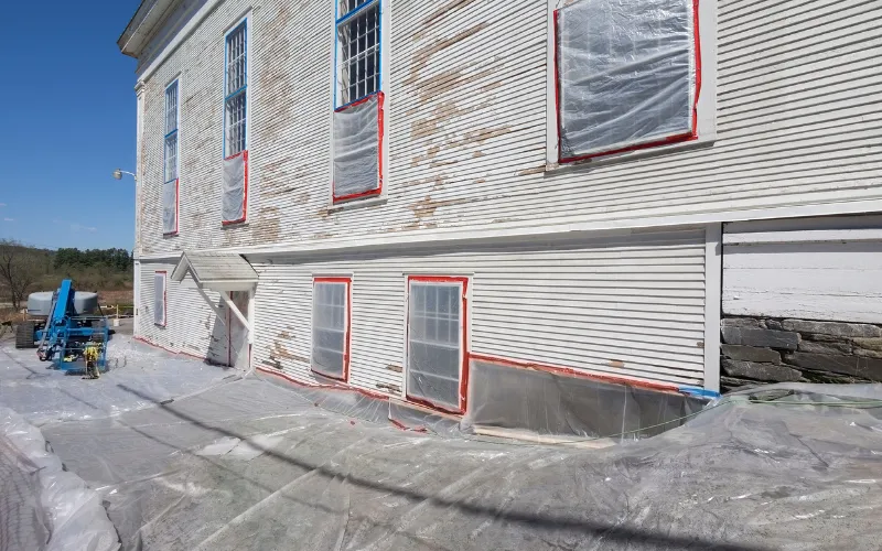 House exterior with windows covered in plastic sheeting